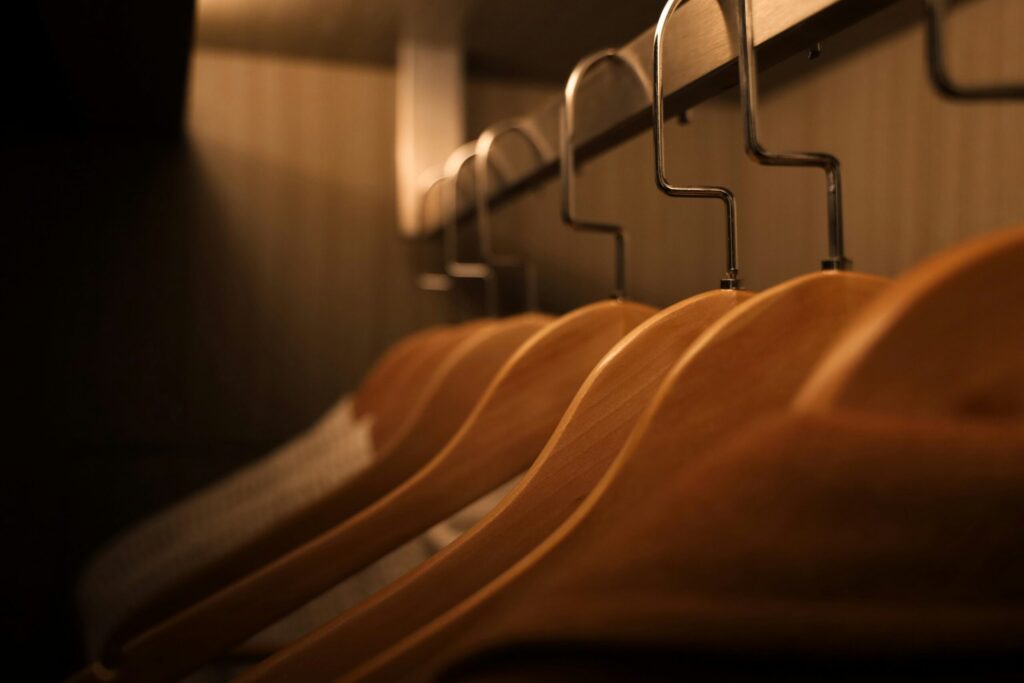 hanging clothes on wooden hangers in a small closet