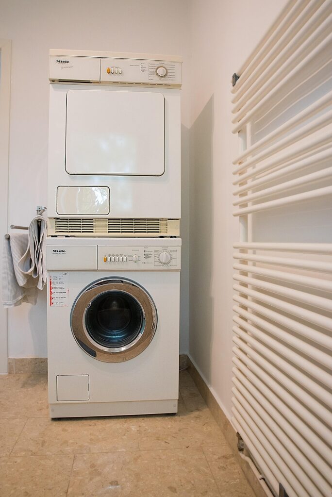 stacked washing machines in a closet turned in a laundry room