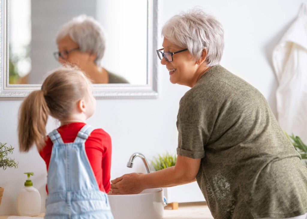 girl and her grandmother are washing hands|