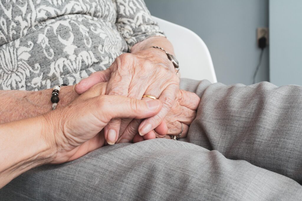 caregiver holding hands with a memory care patient|woman smiling in Kohler walk-in bath|KOHLER Ice Grey LuxStone Shower Walls|Little girl and her grandma brushing teeth in bathroom|elderly couple holding hands